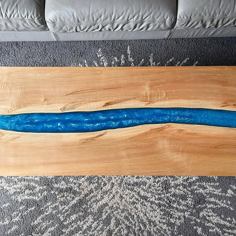 Instagram post by @cbam: 2” live edge cherry slab milled down and rearranged into a river table, filled with blue epoxy resin